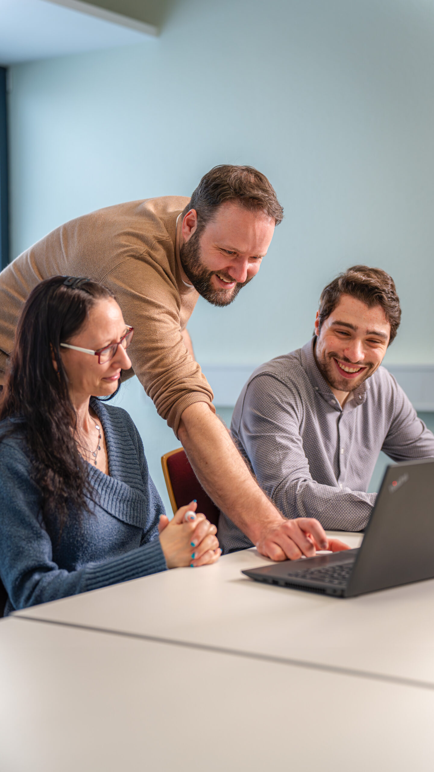 Ein engagiertes Team bei der Zusammenarbeit an einem Laptop, um maßgeschneiderte Payroll-Outsourcing-Lösungen zu entwickeln.