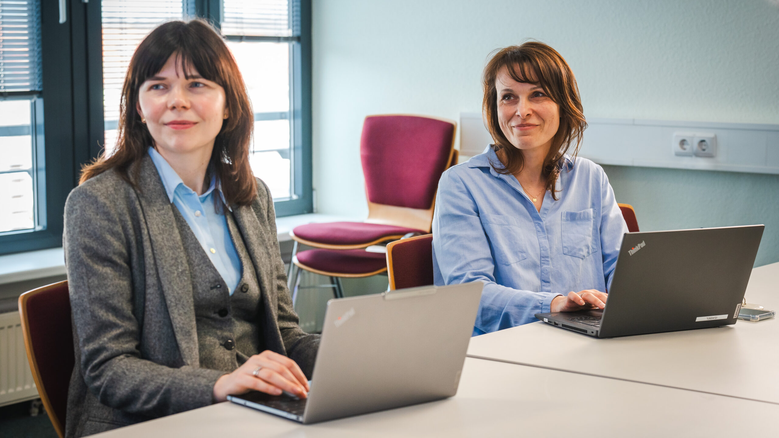 Zwei Frauen im Business-Outfit arbeiten gemeinsam an einem Laptop und besprechen Steuer- und Lohnbuchhaltungsfragen.
