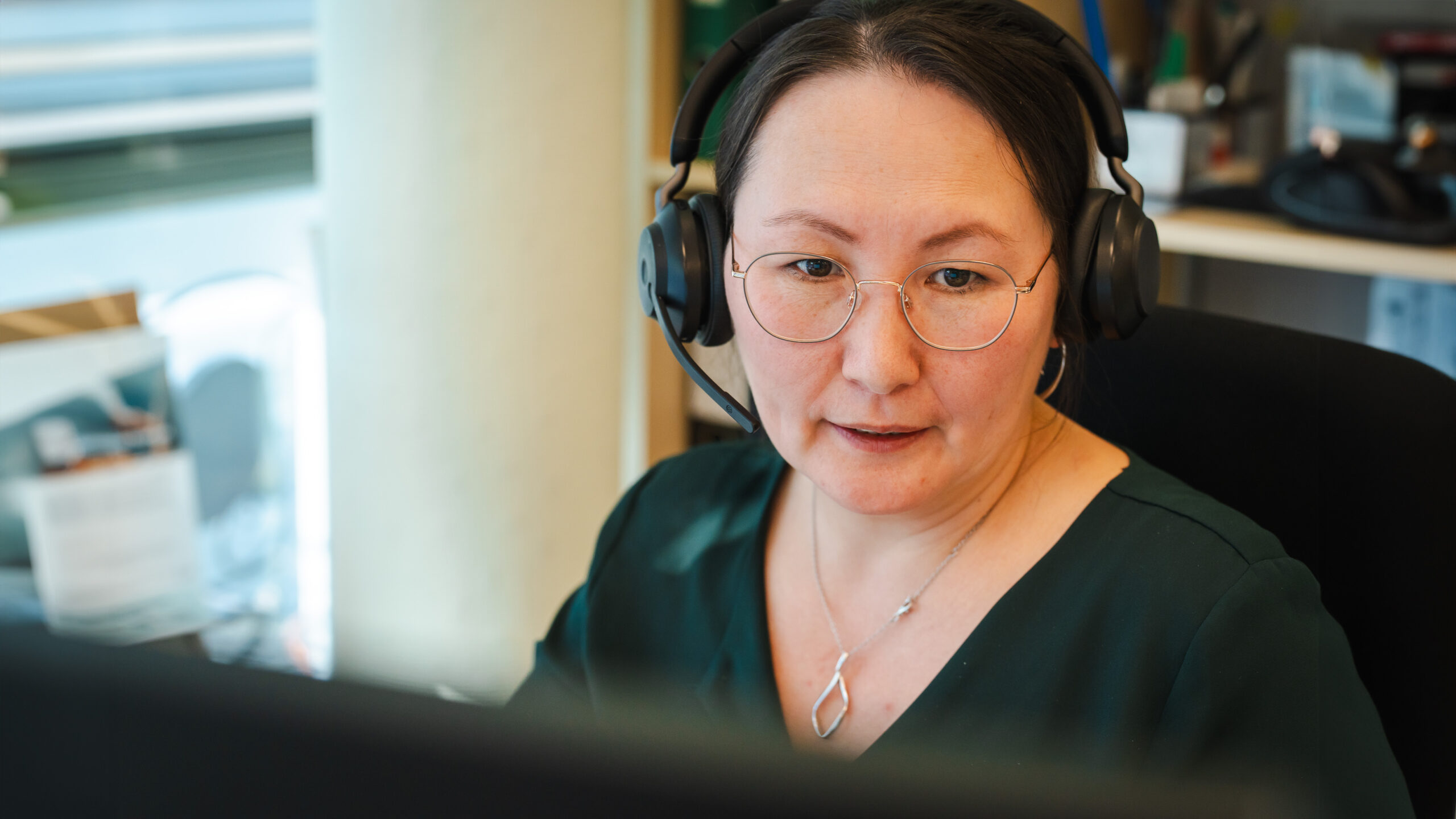 Eine Beraterin mit Headset spricht mit einem Kunden und bietet professionelle Unterstützung bei der Gehaltsabrechnung.